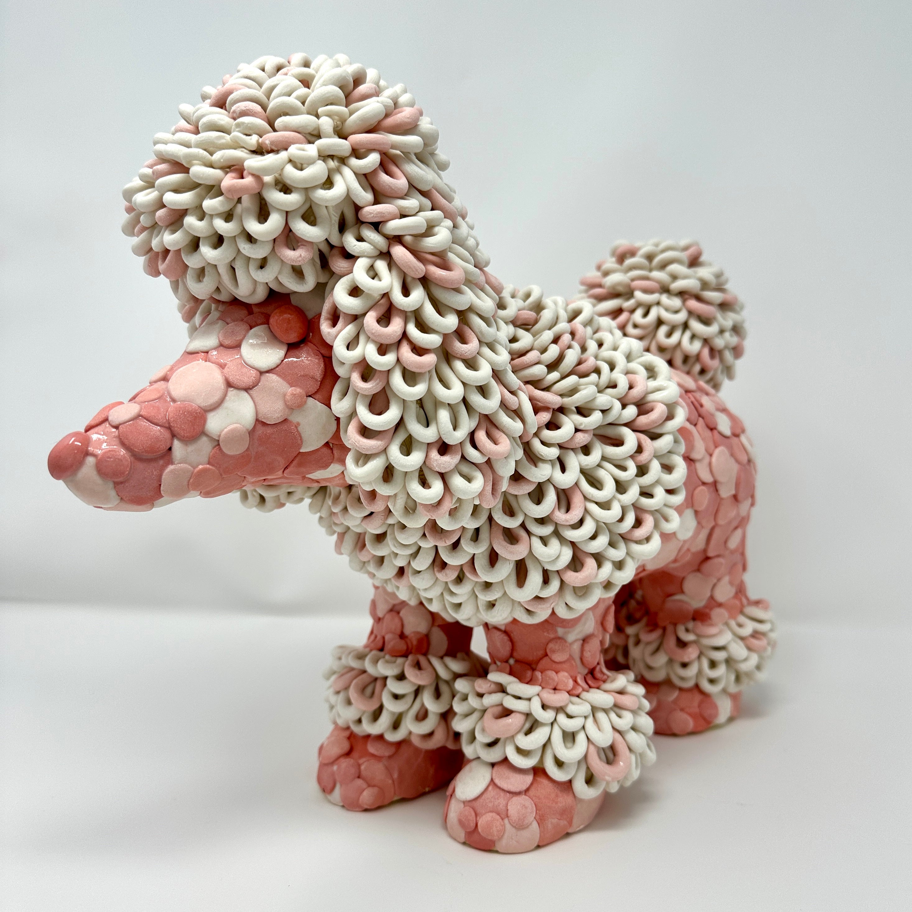 Pink and white ceramic dog sculpture on a light gray background