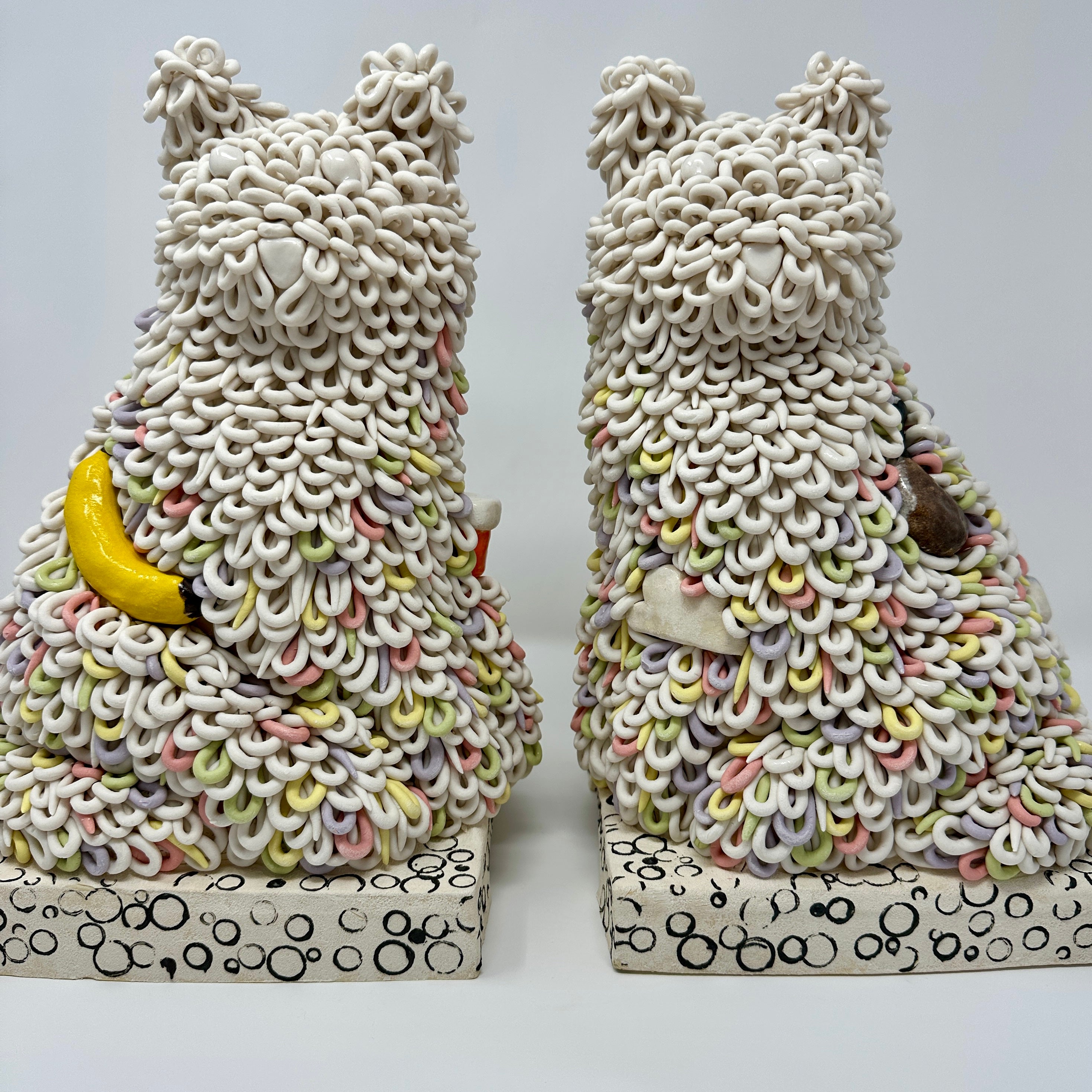 Two decorative cat-shaped objects with textured fur pattern on a white background