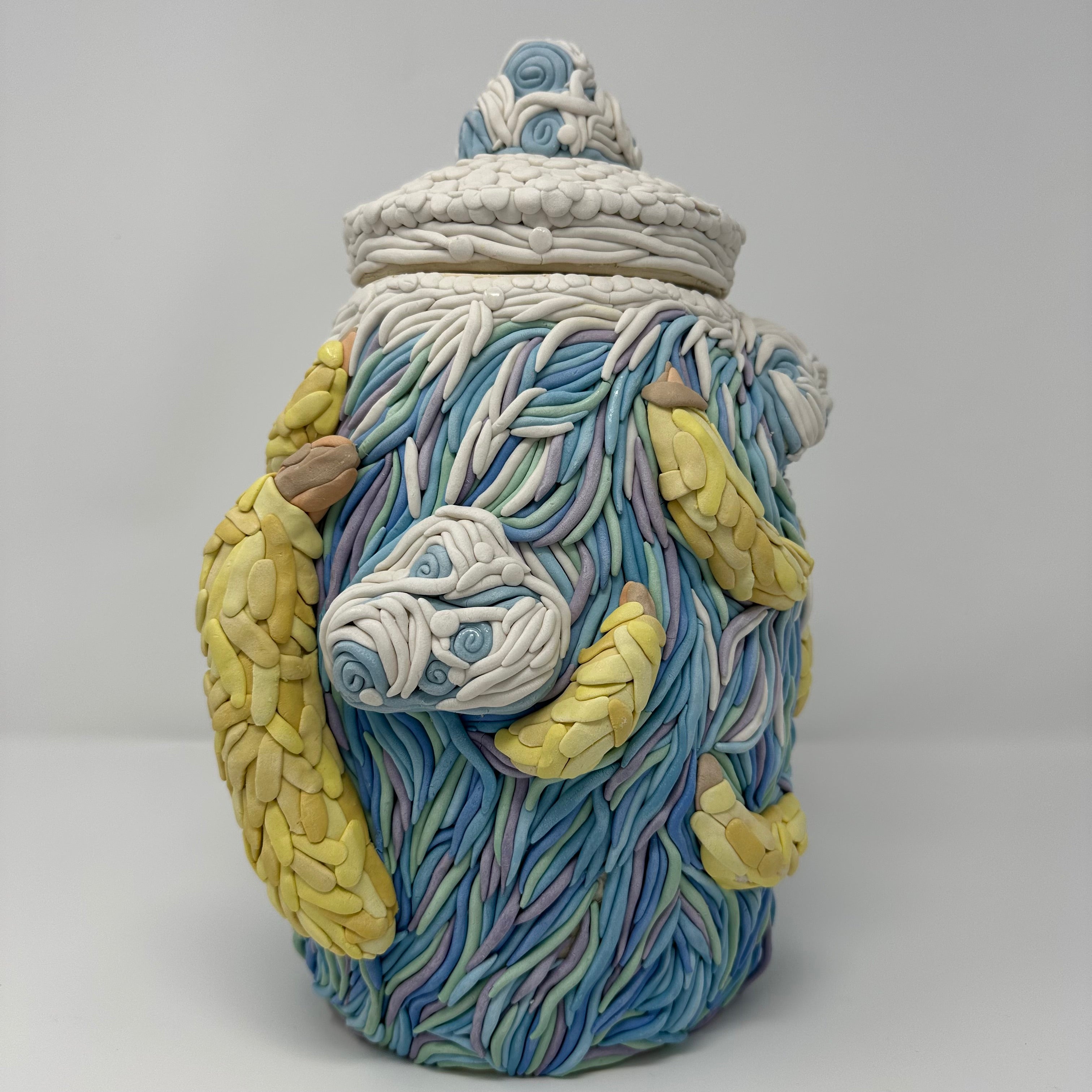 Decorative ceramic jar with colorful designs of clouds and bananas on a white background
