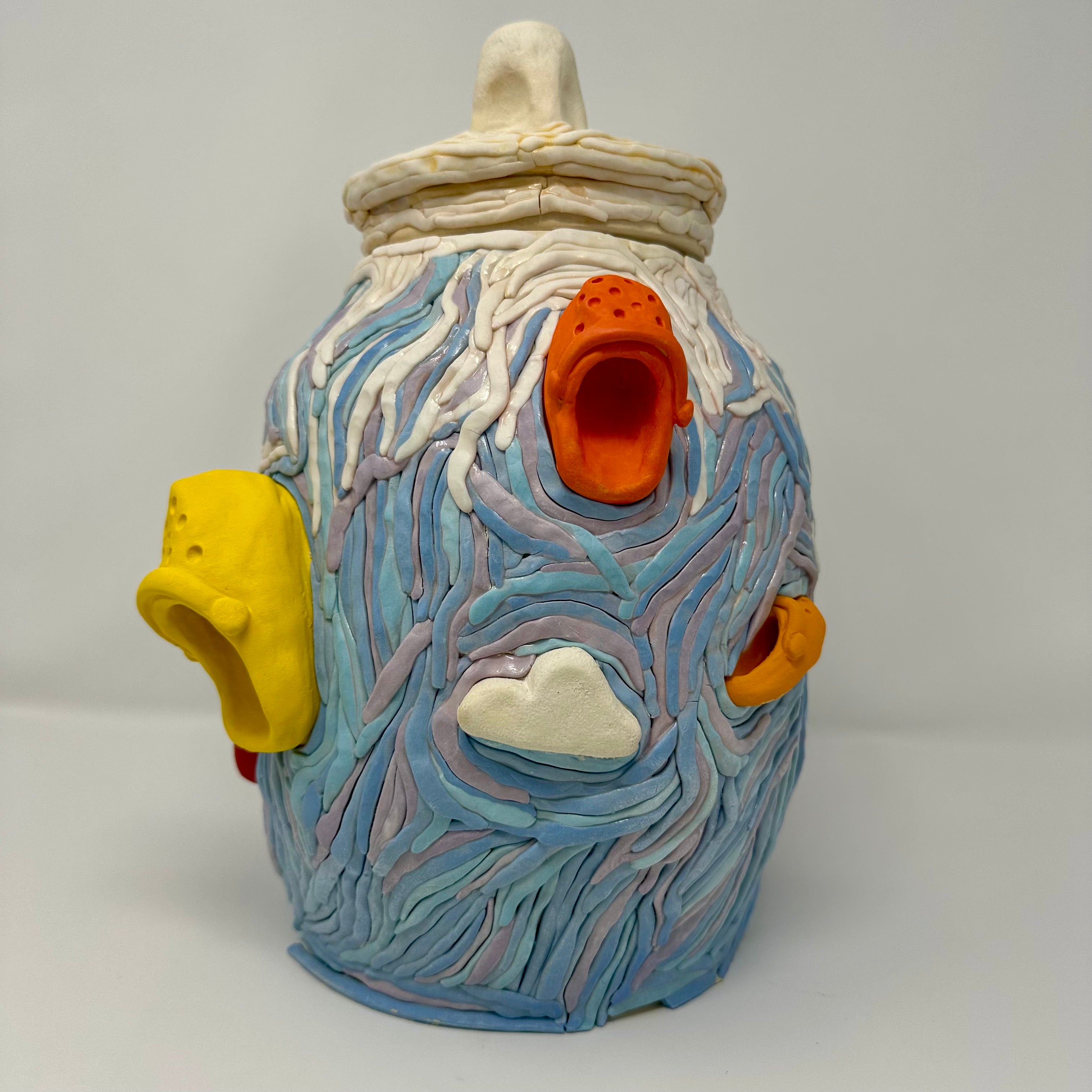 Decorative ceramic jar with colorful designs of Crocs and clouds on a white background
