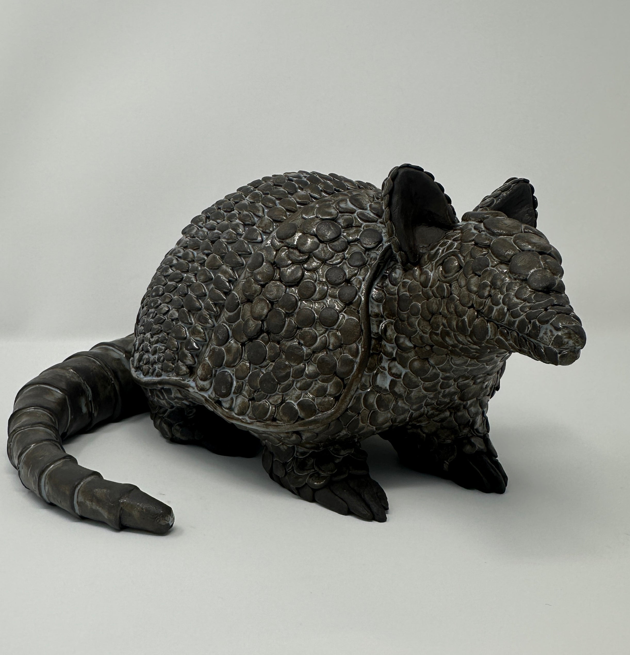 Dark gray armadillo figurine on a light gray background